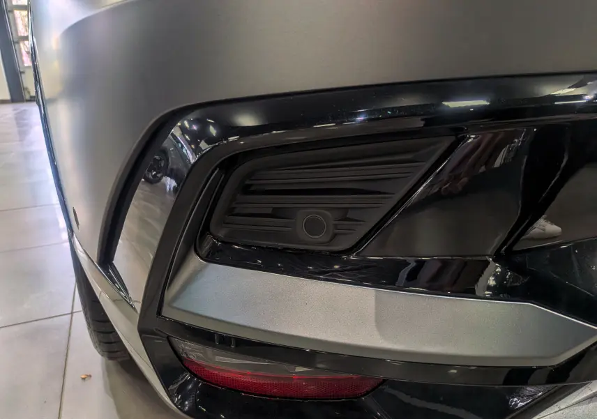 Gros plan sur le pare-chocs avant droit gris Schiste Satin du Renault Rafale 2025 avec capteur de stationnement intégré.