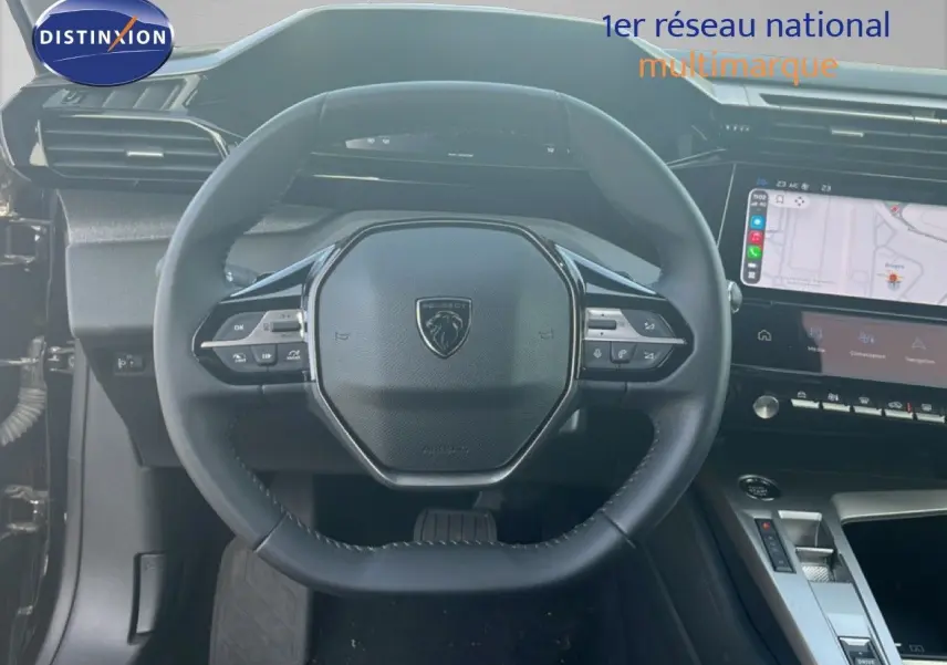 Vue intérieure centrée sur le volant cuir noir de la Peugeot 408 1.2 Hybrid 2025 avec tableau de bord numérique et écran tactile.