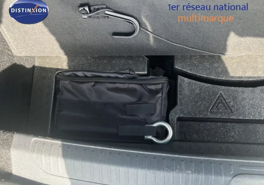 Vue rapprochée du coffre de la Peugeot 408 noir métal, montrant un kit de secours et un crochet de remorquage.