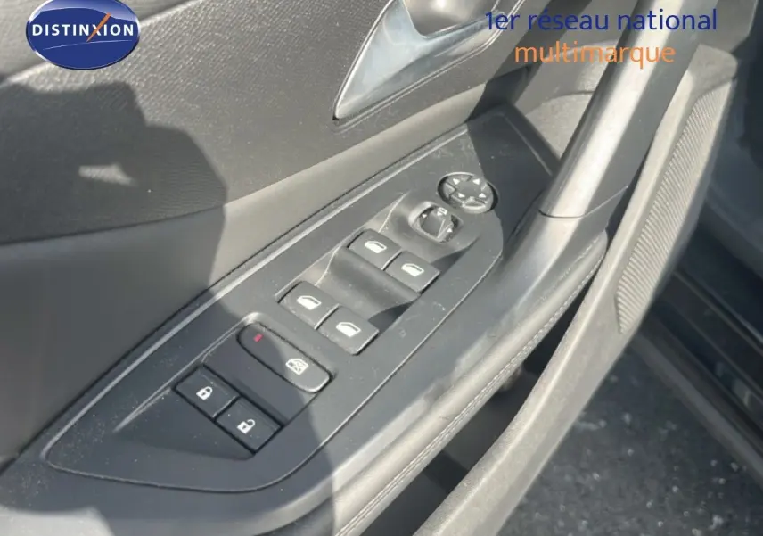 Gros plan sur la commande des vitres et des rétroviseurs côté conducteur d’une Peugeot 408 noire métal, intérieur gris.