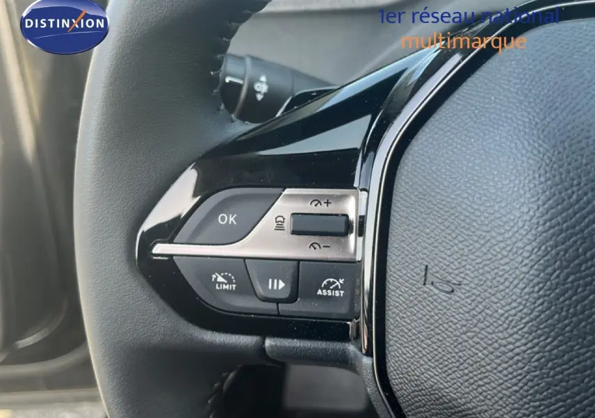 Détail du volant noir de la Peugeot 408 1.2 Hybrid 145ch avec commandes intégrées et finition brillante.