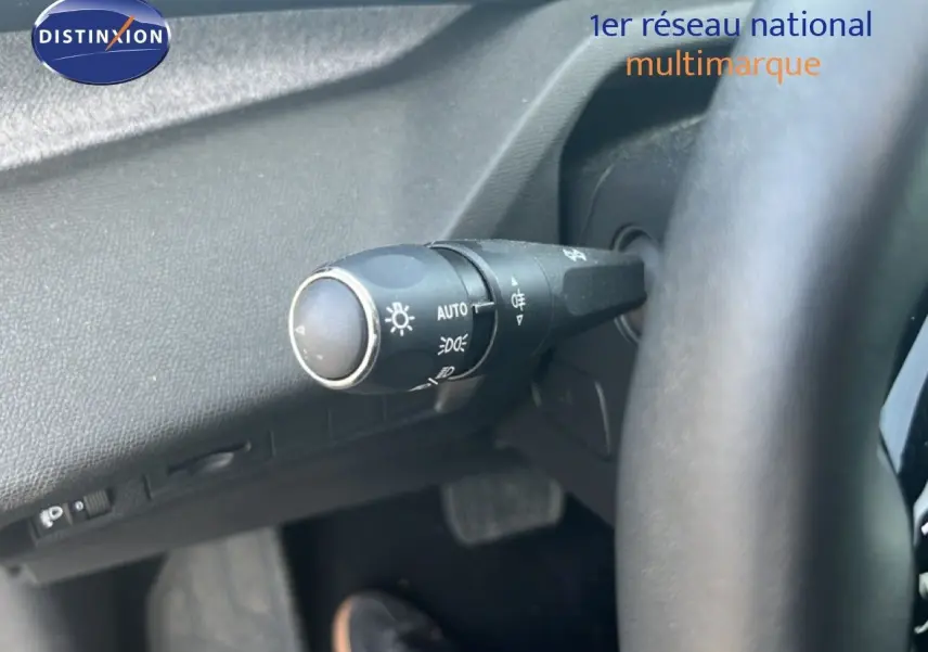Gros plan sur la commande des phares à gauche du volant d’un Peugeot 408 noir métal, intérieur moderne.