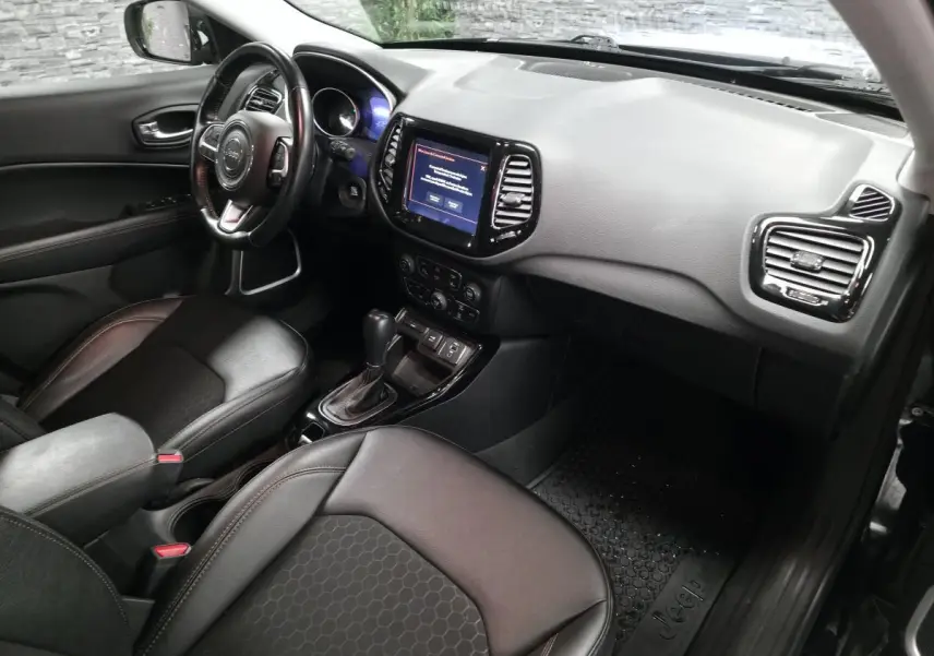 Vue intérieure côté conducteur du Jeep Compass 2021 avec sellerie simili cuir noire et écran tactile central.