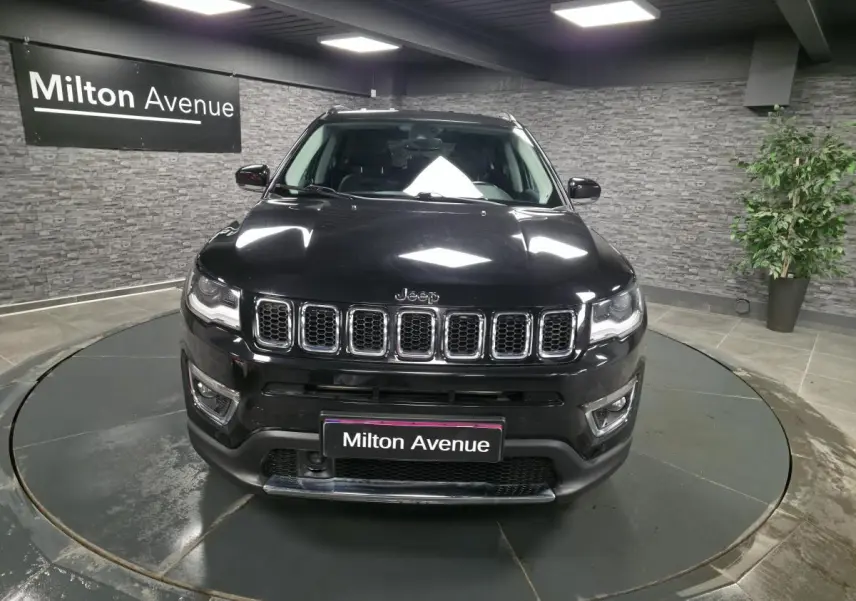 Vue de face du Jeep Compass noir 2021 avec calandre chromée et projecteurs LED dans un showroom.