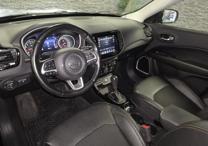 Intérieur avant droit du Jeep Compass noir 2021, volant cuir, écran tactile central et sièges simili cuir.