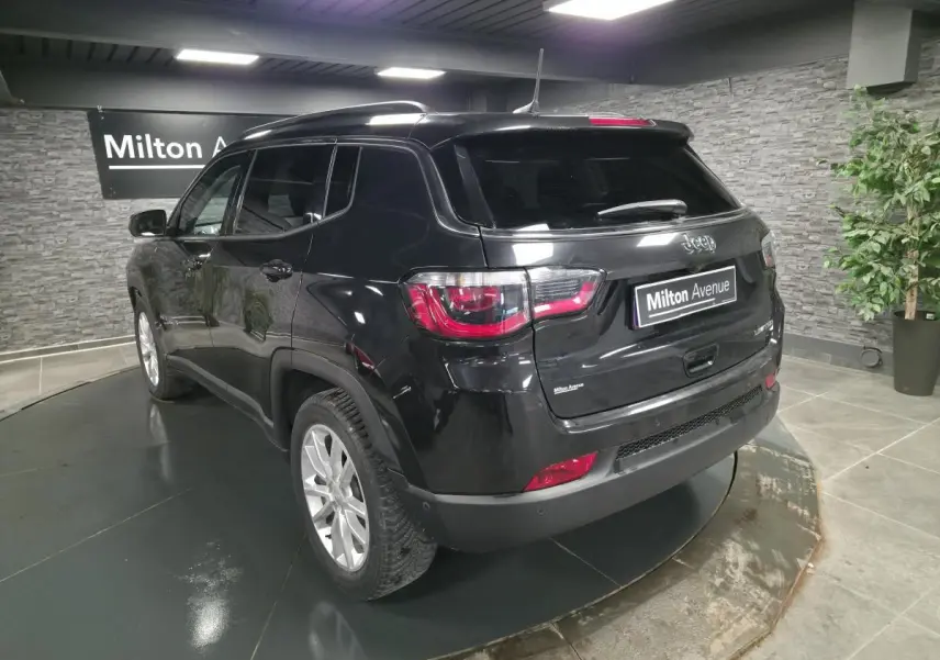 Jeep Compass noir en 3/4 arrière droit dans un showroom avec jantes alliage 18 pouces et vitres surteintées.