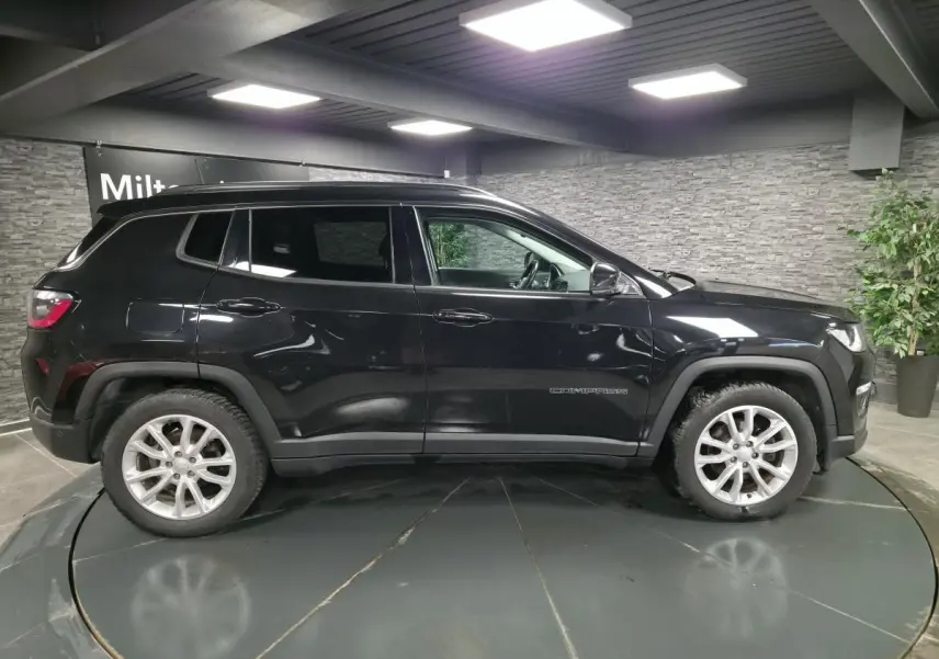 Vue de profil côté gauche d'un Jeep Compass noir, avec jantes alliage 18 pouces et vitres surteintées.