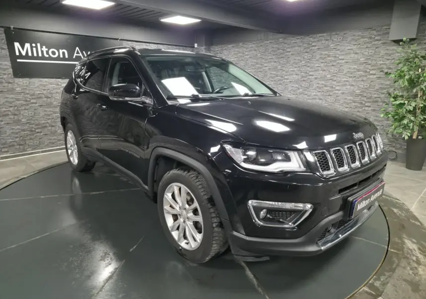 Jeep Compass noir en 3/4 avant droit, avec calandre chromée et jantes alliage 18 pouces visibles en intérieur showroom.