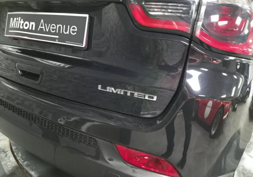 Gros plan sur l'arrière droit noir brillant d'un Jeep Compass Limited avec feux rouges et logo visible.