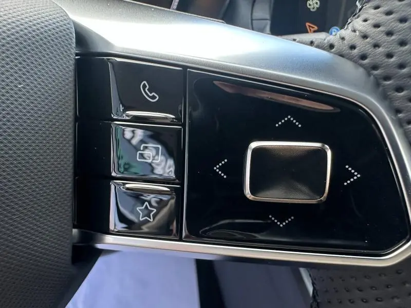 Gros plan sur les commandes noires brillantes du volant multifonction cuir du MG ZS Hybrid+ 2025.