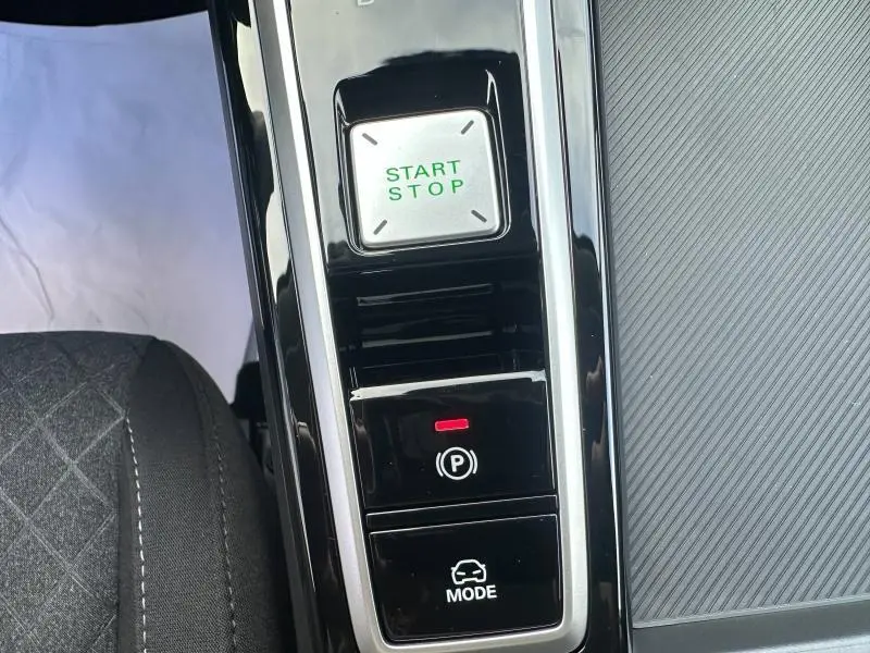 Gros plan sur la console centrale intérieure du MG ZS Hybrid+ blanc, montrant les boutons Start/Stop, frein à main électronique et mode de conduite.