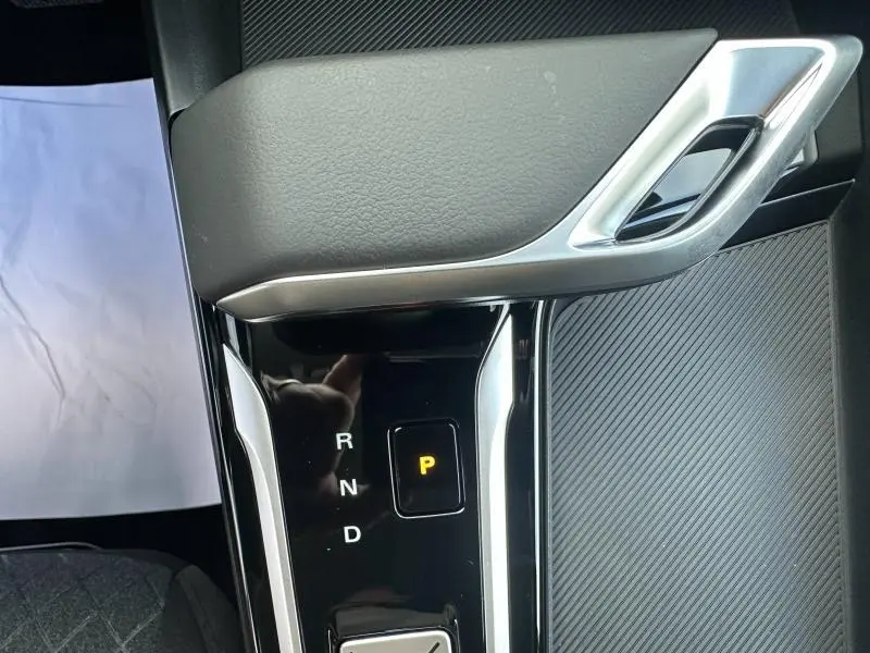 Gros plan sur la console centrale noire avec levier de vitesses automatique en position parking du MG ZS Hybrid+ blanc.