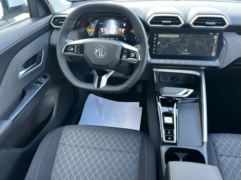 Vue intérieure avant du MG ZS Hybrid+ blanc 2025, volant cuir multifonction et écran tactile GPS au centre.