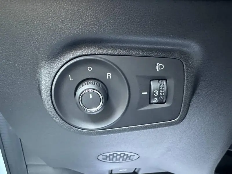 Gros plan sur les commandes noires d'ajustement des rétroviseurs et de réglage des phares du MG ZS Hybrid+ blanc 2025.