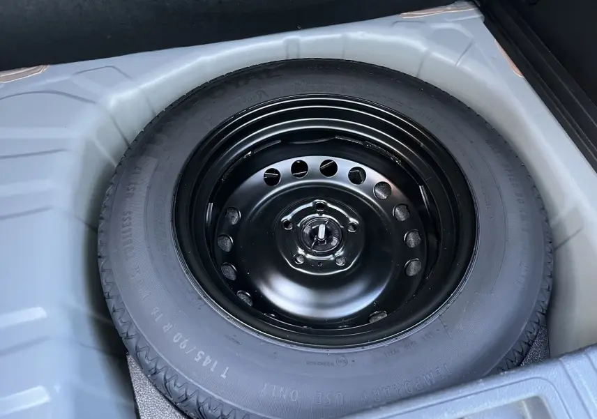 Pneu de secours noir en gros plan dans le coffre d’un Renault Captur gris Rafale toit noir 2025.