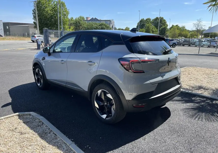 Vue 3/4 arrière droite du Renault Captur 2025 gris Rafale avec toit noir et jantes noires bicolores.