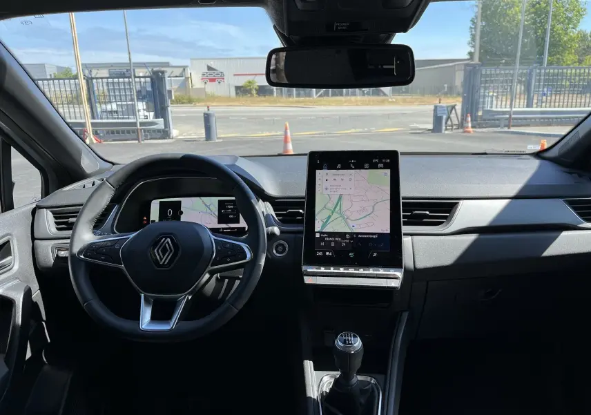 Vue intérieure frontale du tableau de bord du Renault Captur 2025 gris rafale, avec écran tactile vertical et boîte manuelle.