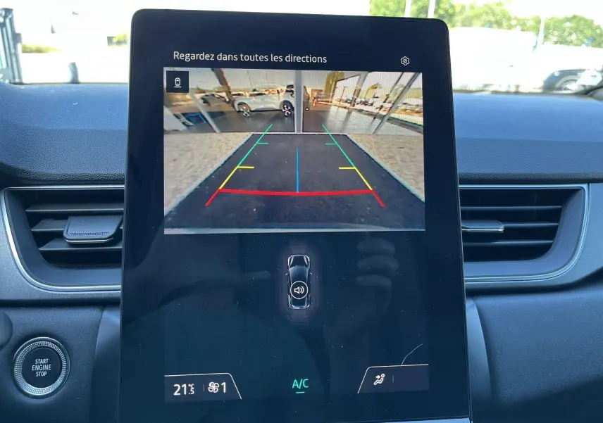 Vue intérieure du tableau de bord du Renault Captur 2025, écran central affichant la caméra de recul avec lignes de guidage colorées.