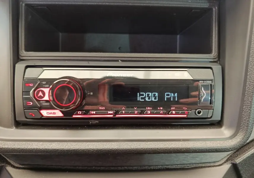 Gros plan sur la radio Pioneer intégrée au tableau de bord de l'AIXAM Ambition gris foncé, affichant 12:00 PM.