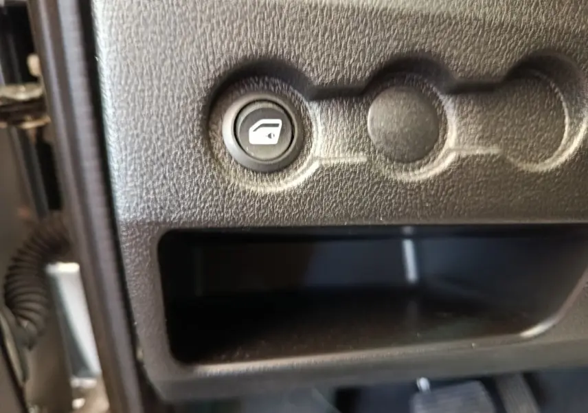 Gros plan sur le bouton de commande de vitre électrique dans l’habitacle gris foncé de l’AIXAM Ambition 0.5 City Crossline Pack 2026.