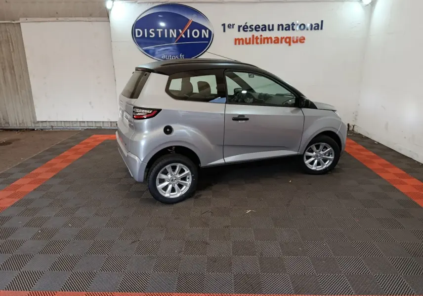 Vue de profil côté gauche d'une Aixam Ambition 0.5 City Crossline Pack gris foncé avec toit noir en intérieur showroom.