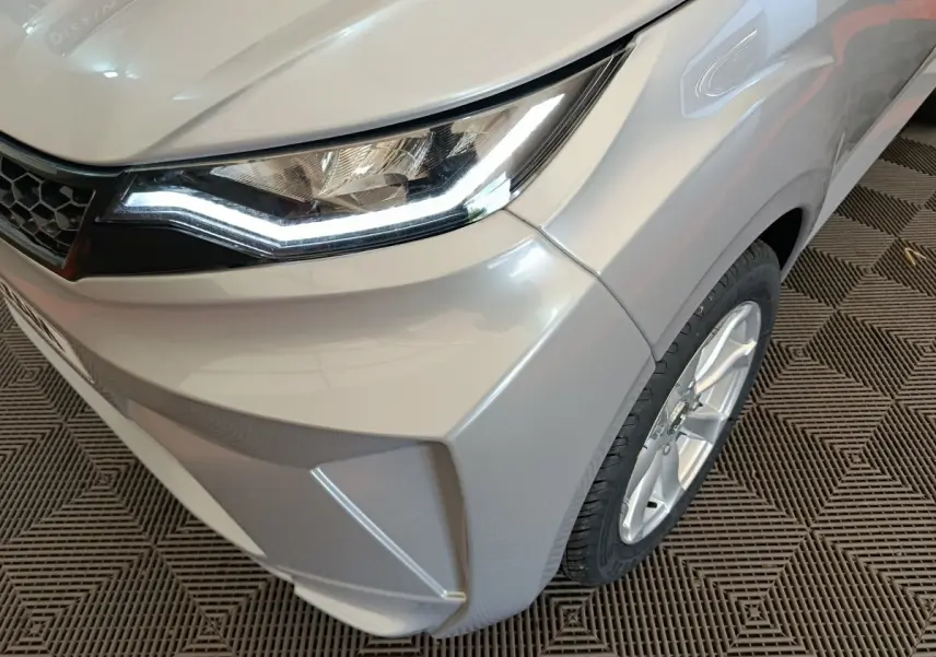 Gros plan sur l'avant droit gris foncé de l'AIXAM AMBITION 0.5 CITY CROSSLINE PACK 2026 avec phare LED allumé.
