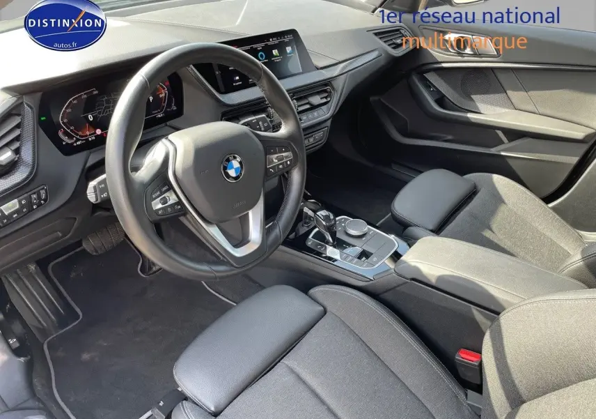 Intérieur BMW Série 1 118i 2021 vu côté conducteur, volant cuir, tableau de bord digital et console centrale moderne.