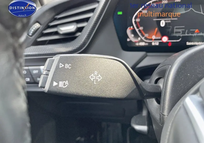 Le levier de clignotant gauche de la BMW Série 1 118i 2021 gris minéral, avec tableau de bord numérique en arrière-plan.