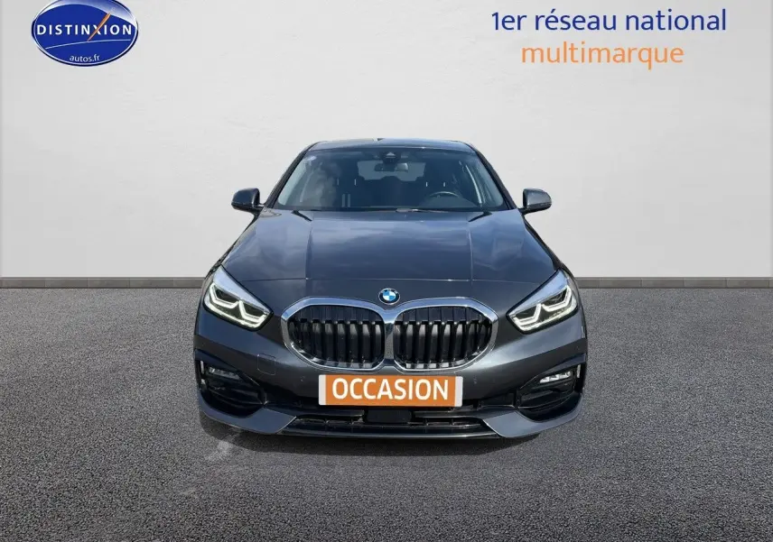 Vue frontale d'une BMW Série 1 gris minéral métal avec calandre double haricot et phares LED allumés.