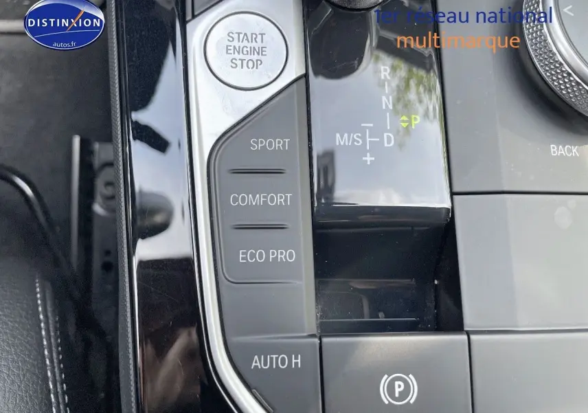 Gros plan sur la console centrale d'une BMW Série 1 gris minéral, avec sélecteur de mode de conduite et bouton start/stop.