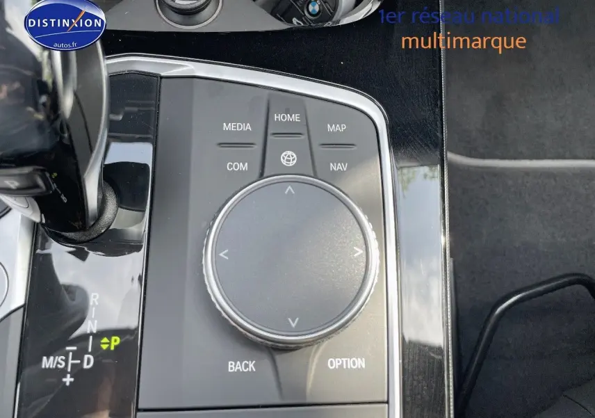 Gros plan sur la molette de commande multimédia et levier de vitesse d'une BMW Série 1 gris minéral 2021.