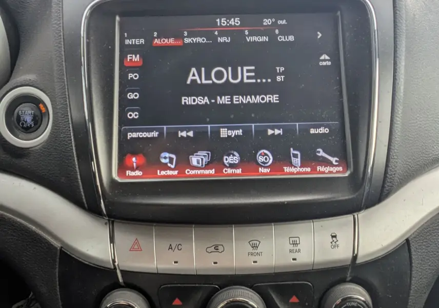 Vue arrière d'un FIAT Freemont gris avec barres de toit et lunette arrière surteintée dans un espace blanc.