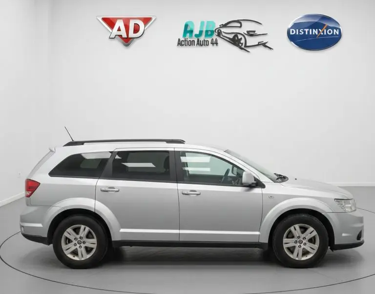 Vue intérieure côté conducteur du Fiat Freemont gris, montrant les sièges avant noirs et le volant cuir.