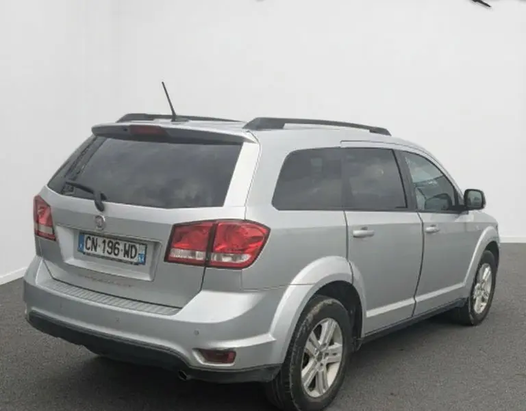 Vue rapprochée du tableau de bord noir du Fiat Freemont 2012, avec écran tactile affichant radio et commandes climatisation.