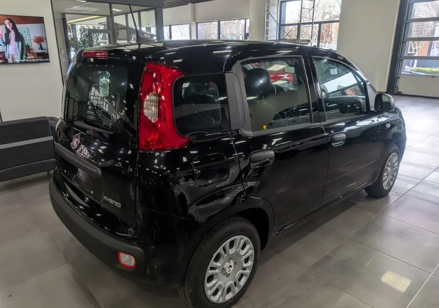 Vue 3/4 arrière droite d'une FIAT Panda 1.0 Hybrid 2025 noir brillant en showroom avec feux arrière rouges.