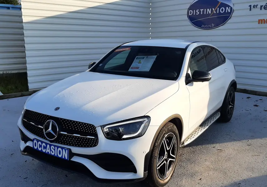Mercedes GLC Coupé 300 4MATIC AMG blanc vu en 3/4 avant droit avec jantes noires et marchepieds métalliques.