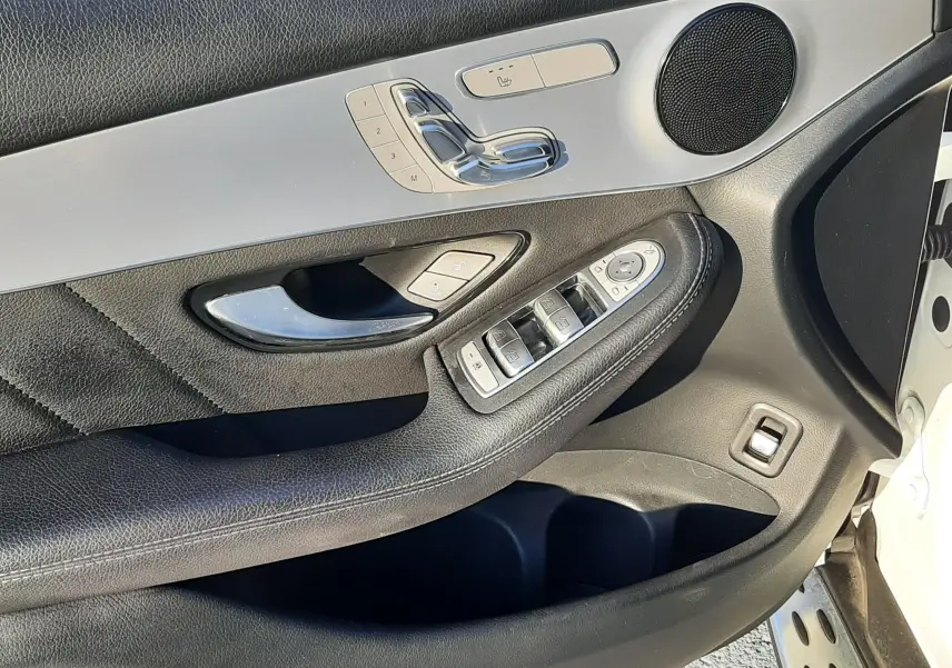 Intérieur côté gauche de la porte d'une Mercedes GLC Coupé blanc, avec commandes sièges chauffants et haut-parleur rond.