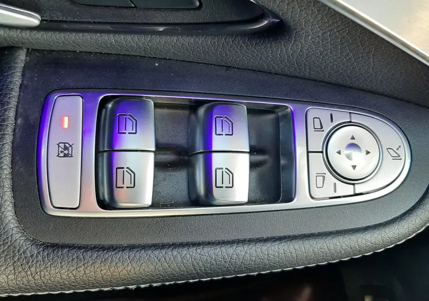 Gros plan sur les commandes des vitres et rétroviseurs côté gauche d'une Mercedes GLC Coupé blanc, finition AMG Line.