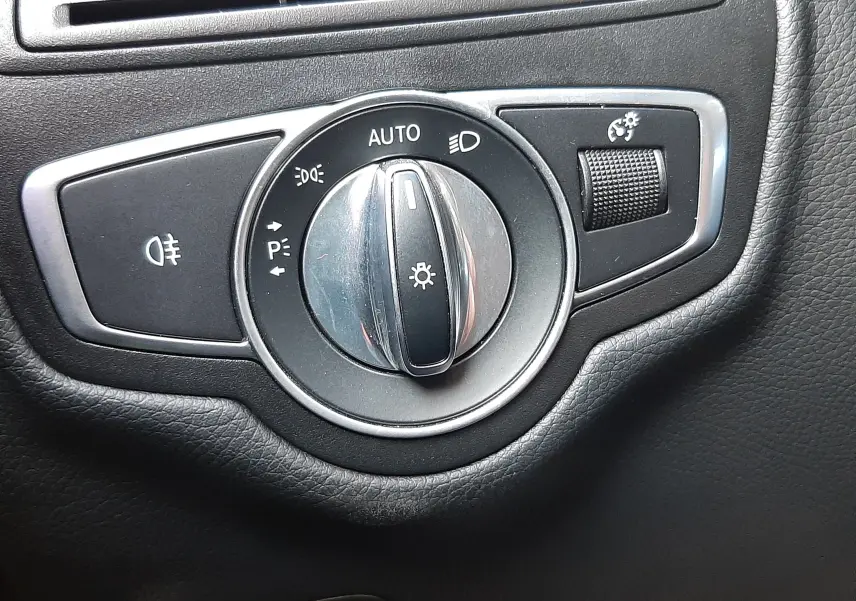 Gros plan sur le bouton de commande des phares et réglage de luminosité intérieur noir du Mercedes GLC Coupé blanc 2019.