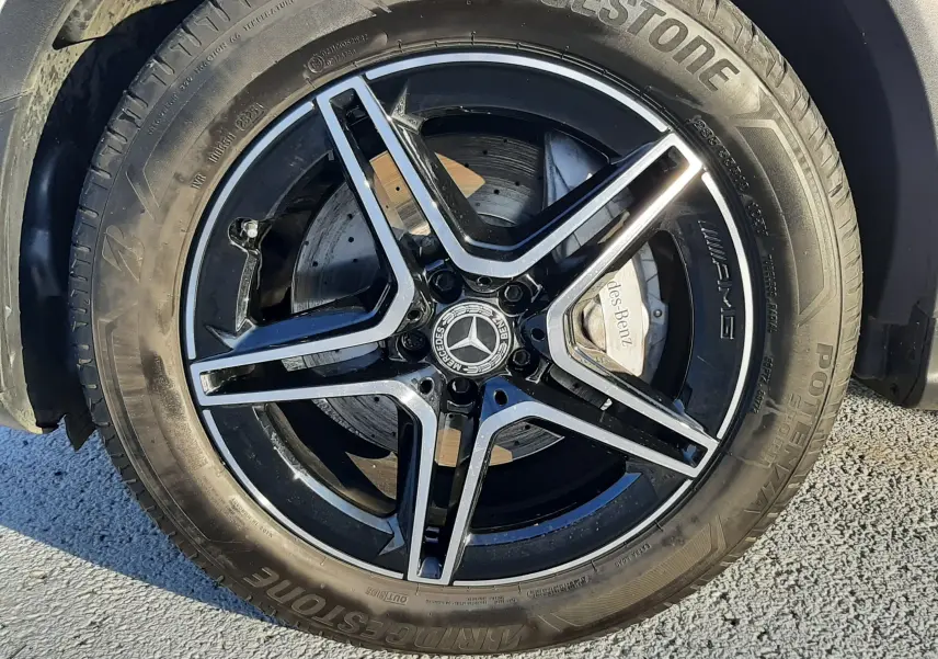 Gros plan sur la jante AMG noire et argentée avec logo Mercedes, montée sur un pneu Bridgestone du Mercedes GLC blanc.