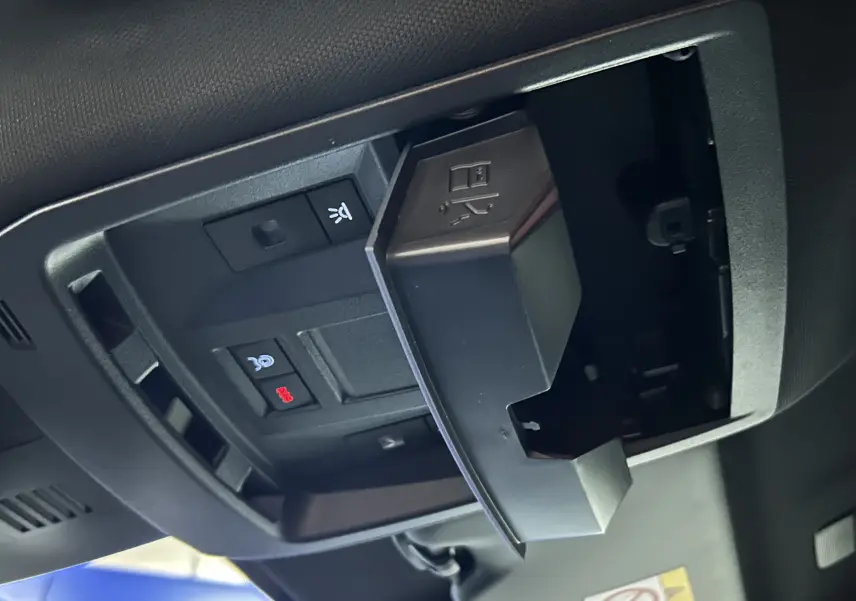 Gros plan sur le compartiment ouvert au plafond avec boutons de contrôle, intérieur noir du Peugeot 3008 III Hybrid 2025.