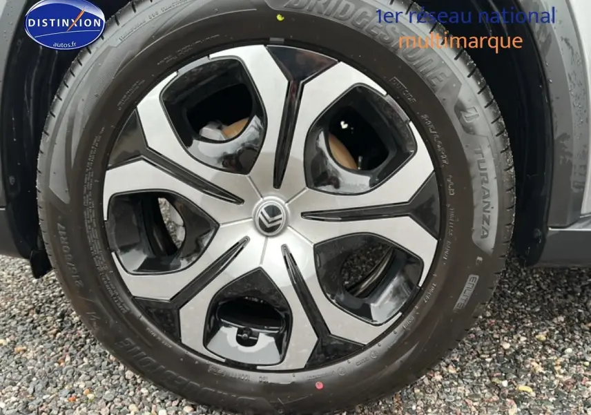 Vue de profil côté droit d'une Citroën C3 Aircross 1.2 turbo gris, avec jantes 17 pouces sur sol gravillonné.