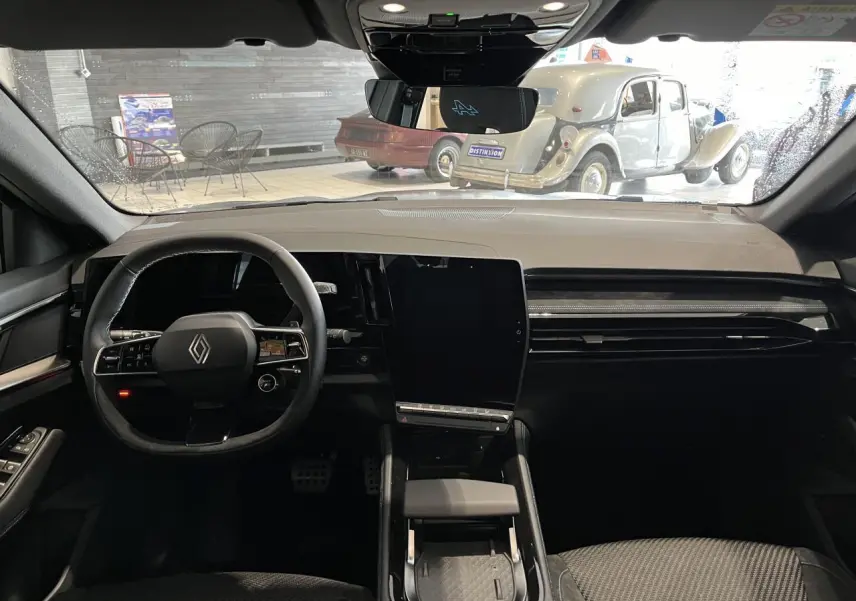 Vue intérieure avant du Renault Austral 2025 gris, avec tableau de bord moderne et grand écran tactile vertical.