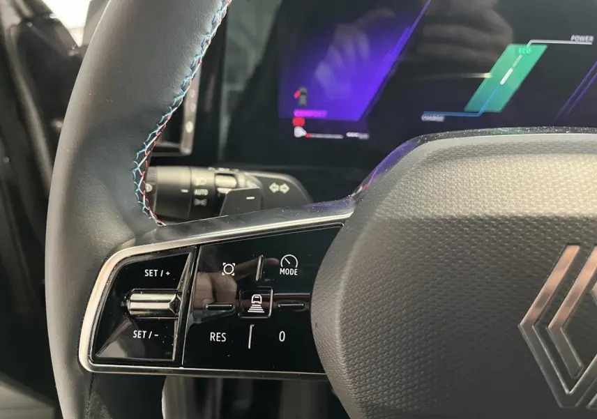 Gros plan sur le volant noir avec surpiqûres bleues du Renault Austral 2025, affichage numérique en arrière-plan.