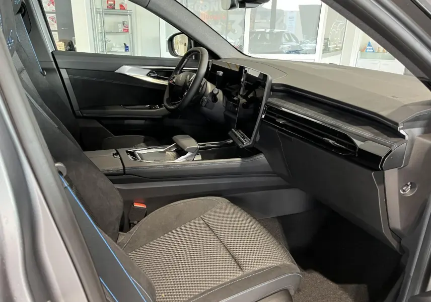 Intérieur côté conducteur du Renault Austral 2025 gris, avec sellerie Alcantara noire et écran tactile central vertical.