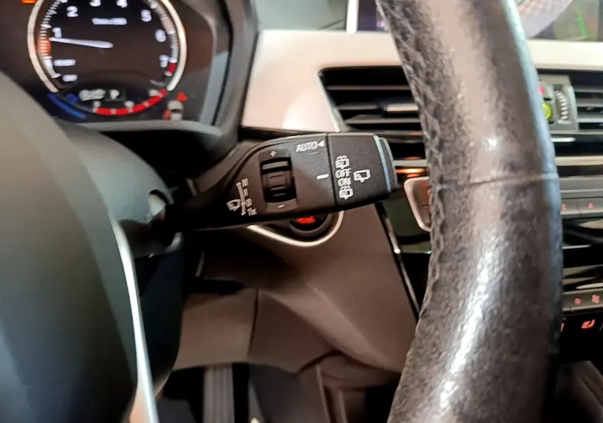 Vue intérieure rapprochée du volant cuir noir et du commodo d’essuie-glace d’une BMW X1 sDrive20i 2020.