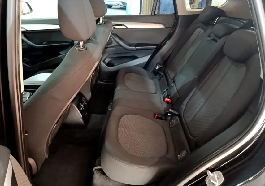 Vue intérieure côté droit sur la banquette arrière noire du BMW X1 sDrive20i Business Design 2020, sièges tissu et appuie-têtes visibles.
