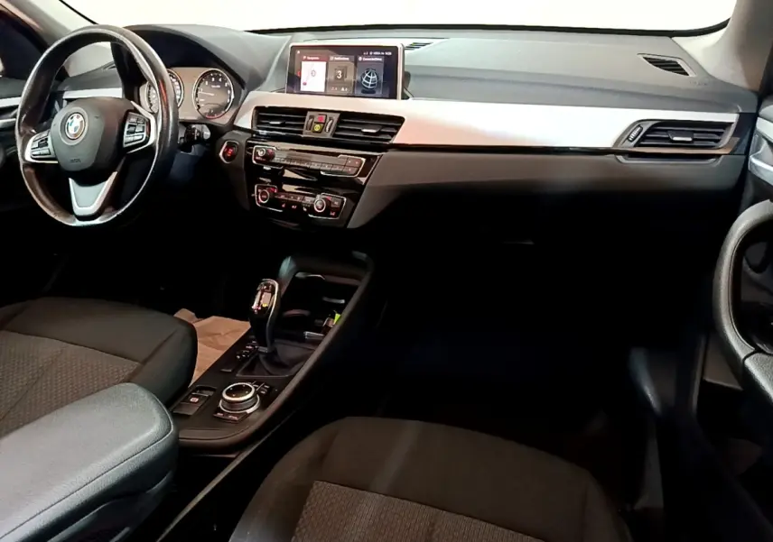 Intérieur noir de BMW X1 2020, vue côté conducteur sur tableau de bord avec écran tactile et volant cuir multifonctions.