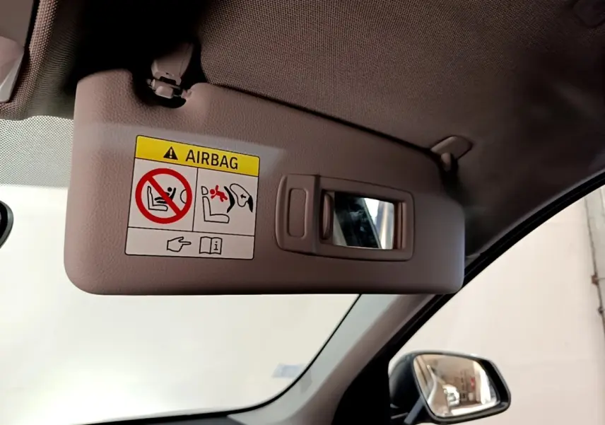 Détail intérieur du pare-soleil côté conducteur avec miroir et avertissement airbag dans une BMW X1 noire de 2020.