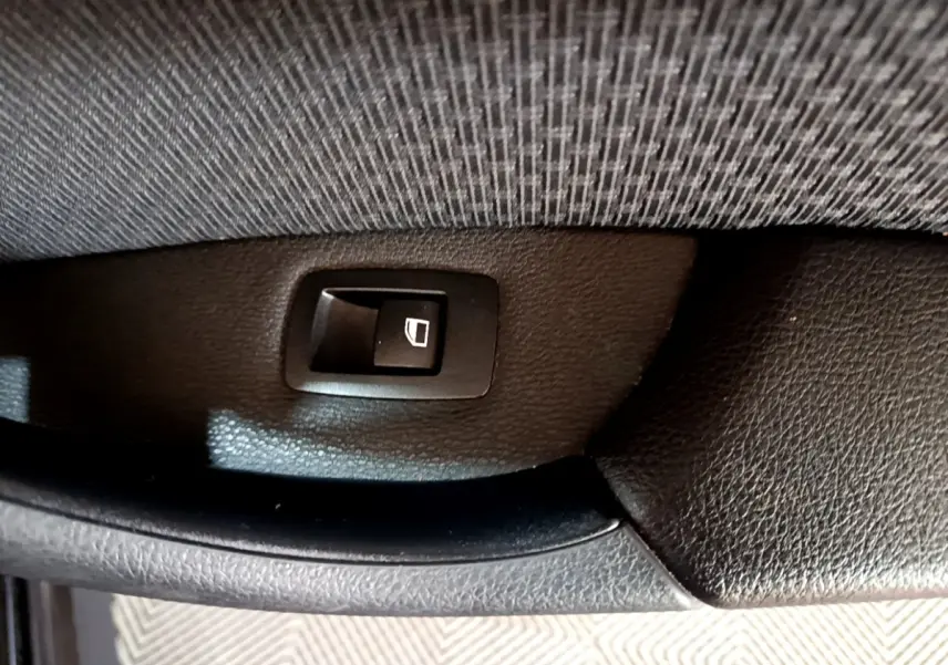Bouton de commande de lève-vitre arrière sur panneau de porte intérieur noir d'une BMW X1 sDrive20i 2020.